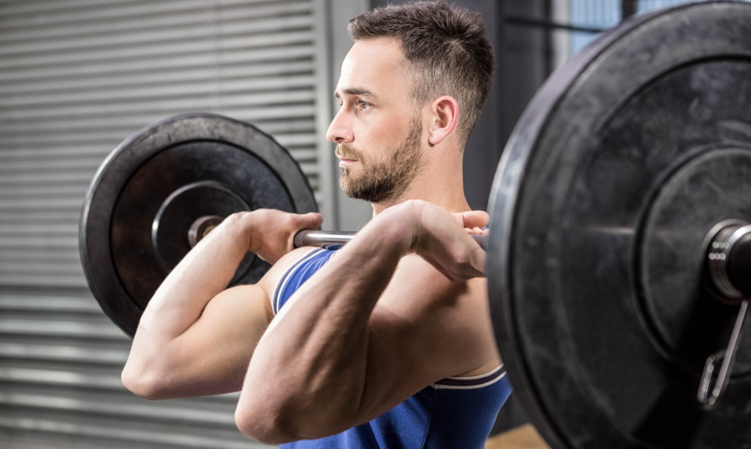 Muscular man lifting barbell at the gym